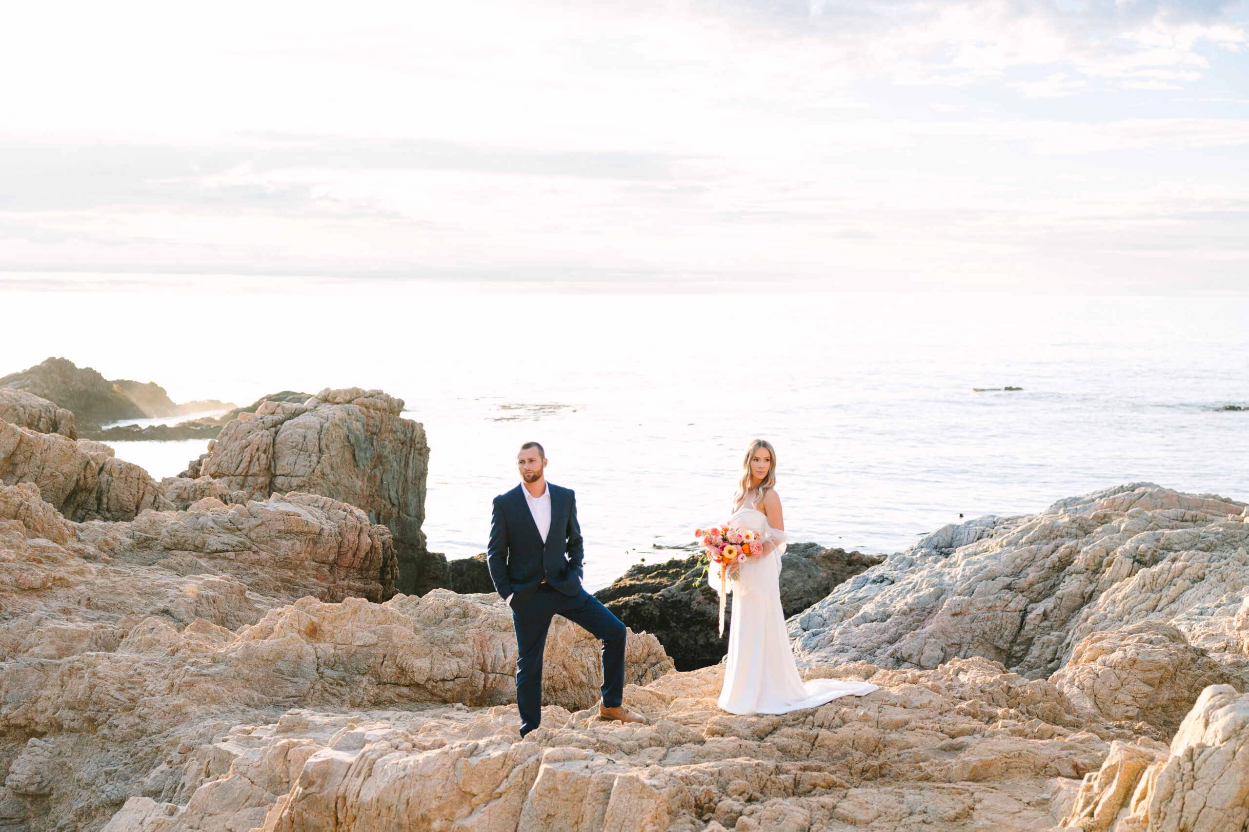 Bride & Groom standing on a rock with big sur ocean views