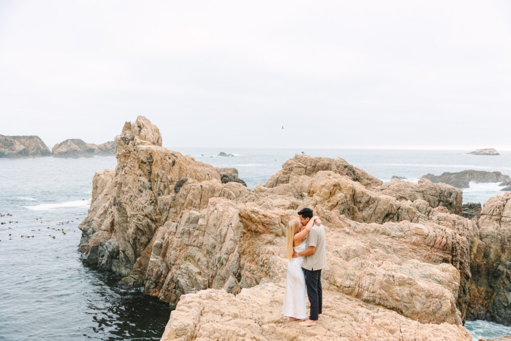 Couple hugging on a rock in Big Sur with an ocean view